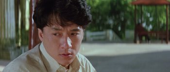 Movie still from “Miracles: The Canton Godfather” (1989), directed by Jackie Chan – A young man in a white dress shirt is looking down; Close Up shot, Low angle