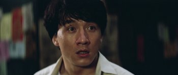Movie still from “Miracles: The Canton Godfather” (1989), directed by Jackie Chan – A person wearing a white shirt; Close Up shot, Low angle