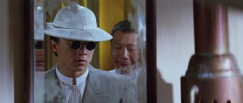 Movie still from “Miracles: The Canton Godfather” (1989), directed by Jackie Chan – A man wearing a white hat and a white suit; Close Up shot, Low angle