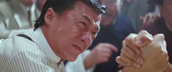 Movie still from “Miracles: The Canton Godfather” (1989), directed by Jackie Chan – An older asian man looking at something on his phone; Close Up shot, Low angle