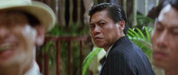 Movie still from “Miracles: The Canton Godfather” (1989), directed by Jackie Chan – A person wearing a suit and tie; Close Up shot, Low angle