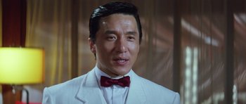Movie still from “Miracles: The Canton Godfather” (1989), directed by Jackie Chan – A person wearing a suit and a red bow tie; Close Up shot, Low angle