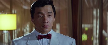 Movie still from “Miracles: The Canton Godfather” (1989), directed by Jackie Chan – A person wearing a suit and a red bow tie; Close Up shot, Low angle