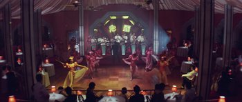 Movie still from “Miracles: The Canton Godfather” (1989), directed by Jackie Chan – A group of people are dancing on a stage; Extreme Wide shot, High angle