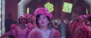 Movie still from “Miracles: The Canton Godfather” (1989), directed by Jackie Chan – A woman in a pink dress and a pink flower hat; Close Up shot, Low angle