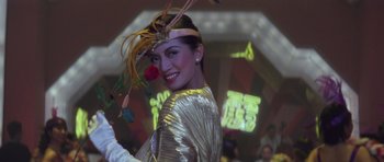 Movie still from “Miracles: The Canton Godfather” (1989), directed by Jackie Chan – A woman in a gold dress holding a red rose; Close Up shot, Low angle