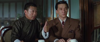 Movie still from “Miracles: The Canton Godfather” (1989), directed by Jackie Chan – Two asian men in suits sitting at a table; Medium shot, Low angle