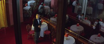 Movie still from “Miracles: The Canton Godfather” (1989), directed by Jackie Chan – A man in a tuxedo standing in front of a mirror; Wide shot, High angle