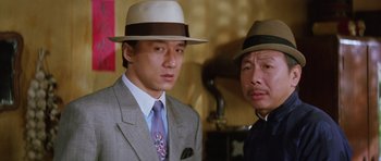 Movie still from “Miracles: The Canton Godfather” (1989), directed by Jackie Chan – Two men in suits and hats posing for a picture; Close Up shot, Low angle