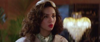Movie still from “Miracles: The Canton Godfather” (1989), directed by Jackie Chan – A person with curly hair wearing a hat; Close Up shot, Over the shoulder angle