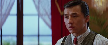 Movie still from “Miracles: The Canton Godfather” (1989), directed by Jackie Chan – A person wearing a suit and a tie; Close Up shot, Low angle