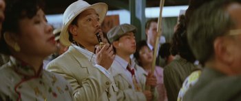 Movie still from “Miracles: The Canton Godfather” (1989), directed by Jackie Chan – A group of men in suits and hats are standing in a crowd; Medium shot, Low angle