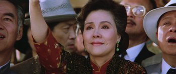 Movie still from “Miracles: The Canton Godfather” (1989), directed by Jackie Chan – An older woman wearing a red and black dress; Close Up shot, Low angle