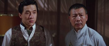 Movie still from “Miracles: The Canton Godfather” (1989), directed by Jackie Chan – Two asian men standing next to each other in front of a window; Close Up shot, Over the shoulder angle