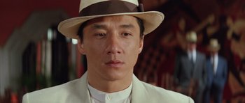 Movie still from “Miracles: The Canton Godfather” (1989), directed by Jackie Chan – A person wearing a suit and hat; Close Up shot, Low angle
