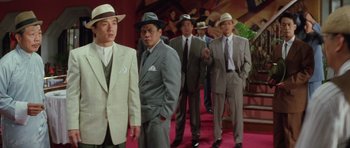 Movie still from “Miracles: The Canton Godfather” (1989), directed by Jackie Chan – A group of men in suits and hats standing next to each other; Medium shot, High angle