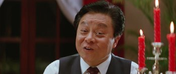 Movie still from “Miracles: The Canton Godfather” (1989), directed by Jackie Chan – An older asian man in a suit and tie; Close Up shot, Low angle