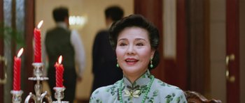 Movie still from “Miracles: The Canton Godfather” (1989), directed by Jackie Chan – An older woman wearing a dress and a bow tie; Close Up shot, Low angle