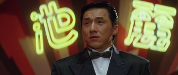 Movie still from “Miracles: The Canton Godfather” (1989), directed by Jackie Chan – A person wearing a suit and a bow tie; Close Up shot, Low angle