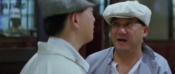 Movie still from “Miracles: The Canton Godfather” (1989), directed by Jackie Chan – A man in a white hat and a man in a white jacket; Close Up shot, Over the shoulder angle