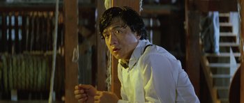 Movie still from “Miracles: The Canton Godfather” (1989), directed by Jackie Chan – A young man with wet hair is looking at the camera; Close Up shot, Low angle