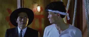 Movie still from “Miracles: The Canton Godfather” (1989), directed by Jackie Chan – A man and a woman standing next to each other; Close Up shot, Low angle