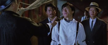Movie still from “Miracles: The Canton Godfather” (1989), directed by Jackie Chan – Two men in suits and ties one of them is crying; Medium shot, Over the shoulder angle
