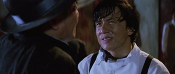 Movie still from “Miracles: The Canton Godfather” (1989), directed by Jackie Chan – A man in a white shirt and a man in a black hat; Close Up shot, Low angle