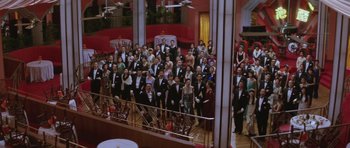 Movie still from “Miracles: The Canton Godfather” (1989), directed by Jackie Chan – A large group of people in tuxedos standing in a room; Extreme Wide shot, High angle