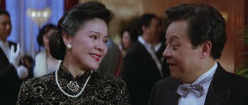 Movie still from “Miracles: The Canton Godfather” (1989), directed by Jackie Chan – A woman and a man are talking to each other; Close Up shot, Over the shoulder angle