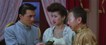 Movie still from “Miracles: The Canton Godfather” (1989), directed by Jackie Chan – A man and two women looking at a cell phone; Close Up shot, Over the shoulder angle