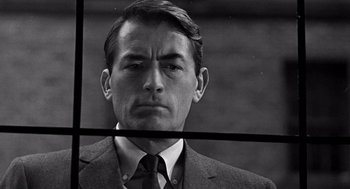 Movie still from “Mirage” (1965), directed by Edward Dmytryk – Black and white photograph of a man in a suit and tie; Close Up shot, Over the shoulder angle