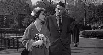 Movie still from “Mirage” (1965), directed by Edward Dmytryk – An old photo of a man and a woman standing next to each other; Medium shot, Over the shoulder angle