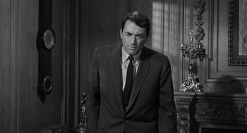 Movie still from “Mirage” (1965), directed by Edward Dmytryk – Black and white photograph of a man wearing a suit and tie; Medium shot, Over the shoulder angle