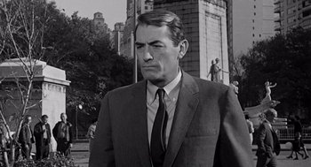 Movie still from “Mirage” (1965), directed by Edward Dmytryk – Black and white photograph of a man wearing a suit and tie; Medium shot, Over the shoulder angle