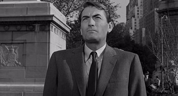 Movie still from “Mirage” (1965), directed by Edward Dmytryk – Black and white photograph of a man wearing a suit and tie; Medium shot, Low angle