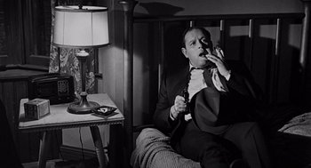 Movie still from “Mirage” (1965), directed by Edward Dmytryk – A black and white photo of a man smoking a cigarette; Medium shot, High angle