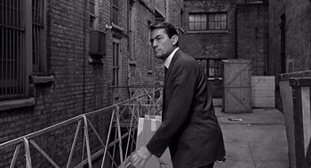 Movie still from “Mirage” (1965), directed by Edward Dmytryk – A black and white photo of a man in a suit and tie; Medium shot, High angle