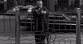Movie still from “Mirage” (1965), directed by Edward Dmytryk – A black and white photo of a man holding a gun; Medium shot, Low angle