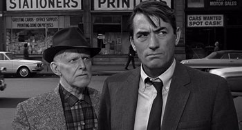Movie still from “Mirage” (1965), directed by Edward Dmytryk – A man and a woman standing next to each other in front of a building; Close Up shot, Over the shoulder angle