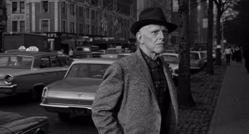 Movie still from “Mirage” (1965), directed by Edward Dmytryk – An older man wearing a hat standing in a parking lot; Medium shot, Low angle