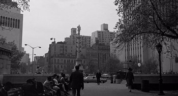 Movie still from “Mirage” (1965), directed by Edward Dmytryk – A black and white photo of people sitting on the sidewalk; Extreme Wide shot, High angle