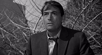 Movie still from “Mirage” (1965), directed by Edward Dmytryk – Black and white photograph of a man wearing a suit and tie; Close Up shot, Low angle