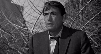 Movie still from “Mirage” (1965), directed by Edward Dmytryk – Black and white photograph of a man wearing a suit and tie; Close Up shot, Low angle