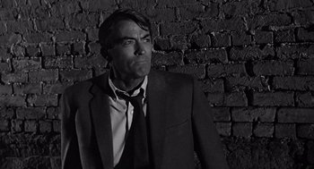 Movie still from “Mirage” (1965), directed by Edward Dmytryk – Black and white photograph of a man wearing a suit and tie; Close Up shot, Low angle