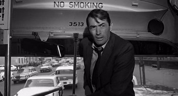 Movie still from “Mirage” (1965), directed by Edward Dmytryk – A black and white photo of a man standing on a bus; Medium shot, Over the shoulder angle