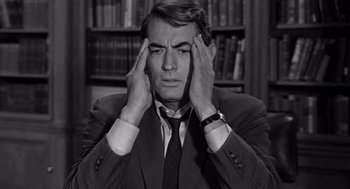 Movie still from “Mirage” (1965), directed by Edward Dmytryk – A black and white photo of a man in a suit holding his hands to his head; Close Up shot, High angle