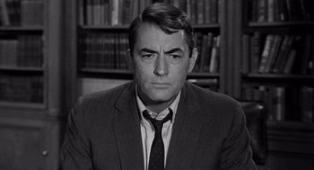 Movie still from “Mirage” (1965), directed by Edward Dmytryk – Black and white photograph of a man wearing a suit and tie; Close Up shot, Over the shoulder angle