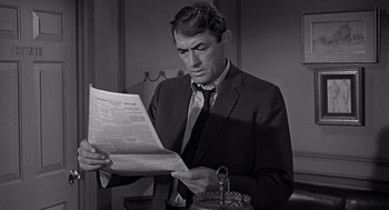 Movie still from “Mirage” (1965), directed by Edward Dmytryk – A black and white photo of a man reading a newspaper; Close Up shot, High angle