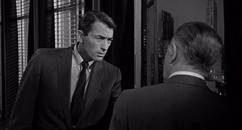 Movie still from “Mirage” (1965), directed by Edward Dmytryk – A black and white photo of a man in a suit looking at a man in a suit; Close Up shot, Over the shoulder angle
